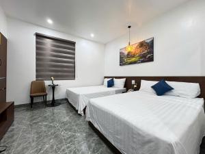 a hotel room with two beds and a window at Khách Sạn MoonKnight 2 in Sầm Sơn