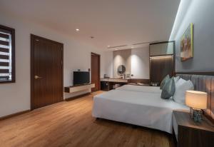 a bedroom with a large white bed and a television at Luxe Paradise Hotel Truc Bach in Hanoi