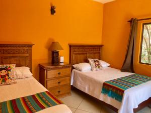 two beds in a room with orange walls at CASONA DOS VIDAS in El Sauz Tequisquiapan +26 photos