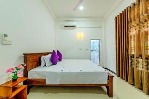a bedroom with a large bed with purple pillows at Ahungalla Ocean Villa in Ahungalla