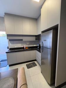 a kitchen with a stainless steel refrigerator and white cabinets at New House, Long Stay in Maringá