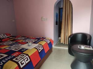 a bedroom with a bed and a black chair at Geobajas Hotels in Imushin
