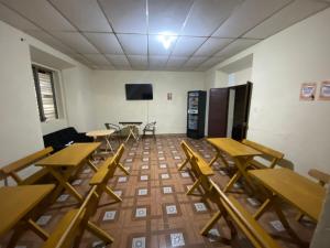 a classroom with wooden tables and chairs and a tv at Hostal Casa Colonial in Santa Ana
