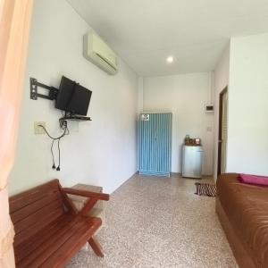 ein Wohnzimmer mit Sofa und Fernseher an der Wand in der Unterkunft The Rusty Plank in Ban Dan Kao