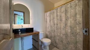 a bathroom with a toilet and a shower curtain at Villa Monarca in Ayampe