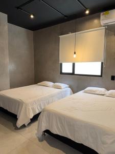 two beds in a room with a window at El marqués casa boutique in Ríohacha