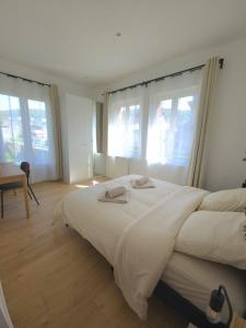 a bedroom with a large white bed with windows at La Tour d'Harfleur 2 in Caudebec-en-Caux