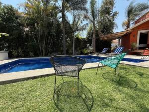 two chairs sitting in the grass near a swimming pool at Loft familiar campestre en Atlixco in Atlixco