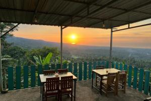 two tables and chairs on a balcony with the sunset at Senaru sunset house in Senaru