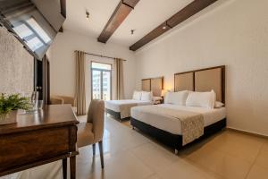 a hotel room with two beds and a desk at Hotel Dorado Plaza Centro Histórico in Cartagena de Indias