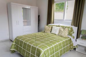 a bedroom with a bed with a green and white blanket at Maysi apartments in Willemstad