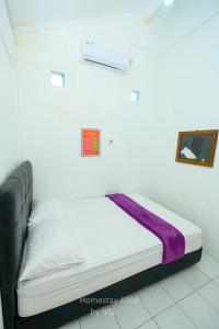 a bed in a room with a purple blanket on it at Homestay Alkid in Timuran