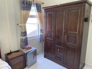 a bedroom with a large wooden cabinet next to a window at Beachside home in Phú Quốc