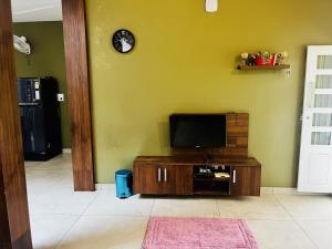 a living room with a tv on a yellow wall at Hidden Serene in Kalpetta