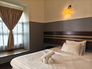 a bedroom with a large white bed with a window at Cozzy Motel Malacca in Malacca +51 photos