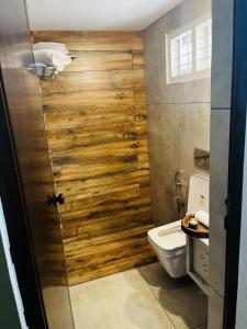 a bathroom with a toilet and a wooden wall at Hidden Serene in Kalpetta +11 photos