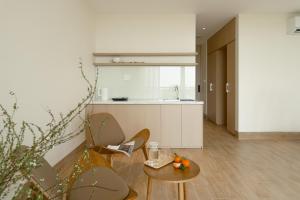 a living room with a table and chairs and a kitchen at Elora House in Thôn Lại Thê