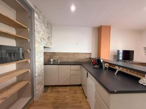 a kitchen with white cabinets and a black counter top at Maison au cœur d’Orgelet in Orgelet +20 photos