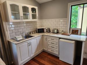 a kitchen with white cabinets and a sink at Hillside Hideaway - Your Base for the Region in Cawongla