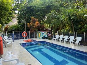 a swimming pool with white chairs and a fence at Cabañas Isla Bonita in Puerto Limón