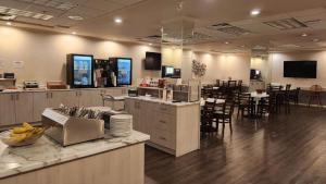 a restaurant with a counter and tables and chairs at Coast Abbotsford Hotel & Suites in Abbotsford