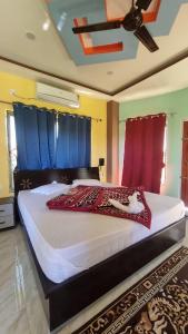 a bedroom with a large bed with blue curtains at North Queen in Lataguri +10 photos