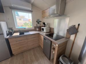 a small kitchen with a sink and a refrigerator at Petit chalet cosy house in Hermanville-sur-Mer +1 photo