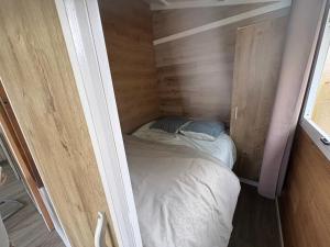 a small room with a bed in a wooden wall at Petit chalet cosy house in Hermanville-sur-Mer