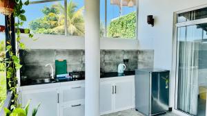 a white kitchen with a sink and a window at Reefline Villa in Weligama