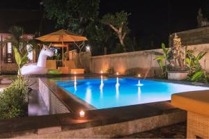een zwembad 's nachts met een eenhoorn in het midden bij Reynold Artha Guest House in Nusa Lembongan