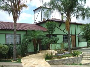 a green building with palm trees in front of it at Pousada Das Candeias in Carrancas
