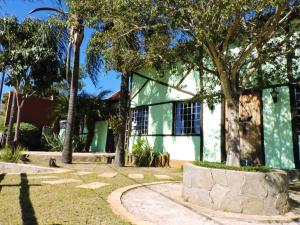 un edificio verde y blanco con árboles y una acera en Pousada Das Candeias, en Carrancas