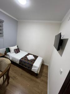 a bedroom with a bed and a tv on a wall at Ichan Kala Silk Road Guest House in Khiva