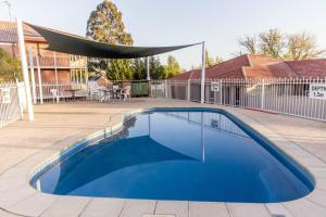 a blue swimming pool with a canopy on a patio at Bathurst Motor Inn in Bathurst