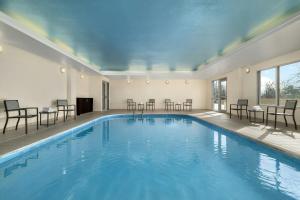 a swimming pool with chairs and tables in a building at Fairfield Inn & Suites Indianapolis Airport in Indianapolis