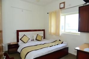 a bedroom with a bed with yellow pillows and a window at Hotel Mount View in Haldwāni
