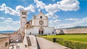 a church with a tower and a clock on it at La Casina appartamento vacanze Assisi in Bastia Umbra