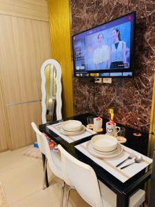 a dining room with a table with white chairs and a tv at Velour Suites in Manila