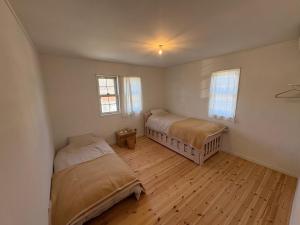 two beds in a room with wooden floors and windows at papan room in Miyota