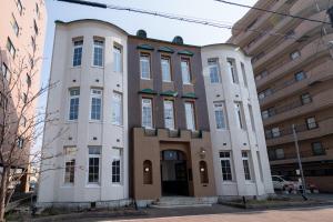 a large white building with windows on a street at T9 Hakodate in Hakodate