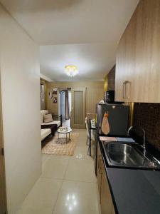 a kitchen with a sink and a living room at Velour Suites in Manila