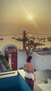 a woman sitting on a ledge looking at the water at Changvilla Đông Hải in Thôn Ðông Giang