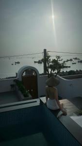 a woman sitting on a ledge next to a swimming pool at Changvilla Đông Hải in Thôn Ðông Giang