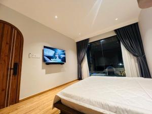 a bedroom with a bed and a tv on the wall at Changvilla Đông Hải in Thôn Ðông Giang