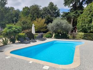 a blue swimming pool with chairs and an umbrella at Hôtel Quai des Pontis in Cognac