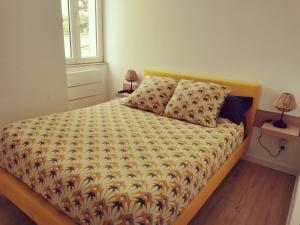 a bed with a comforter and pillows in a bedroom at La Monaco du Nord in Granville