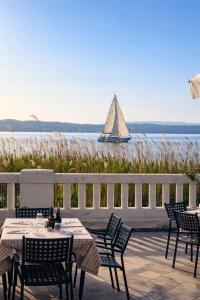 a sail boat in the water with a table and chairs at Hotel Villa Trieste in Sirmione