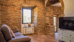 a living room with a stone wall and a tv at La Torre del Vilar in Santa Eulalia de Ríuprimer