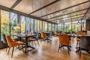 a restaurant with tables and chairs and large windows at Hôtel Quai des Pontis in Cognac