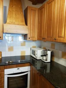 a kitchen with wooden cabinets and a white microwave at Casa Rural Cal Puyo in Paúls